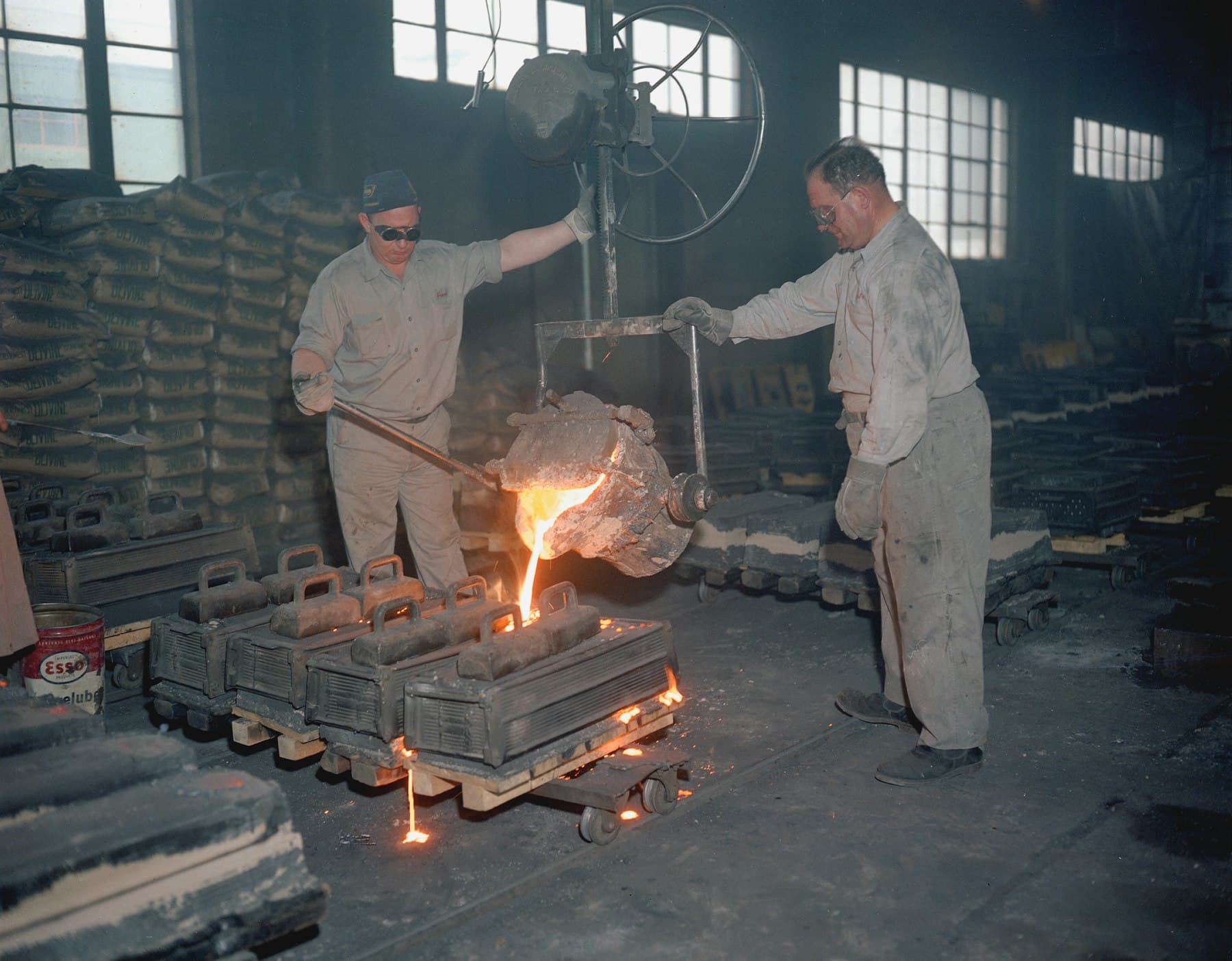Two workers handling metal on a factory floor